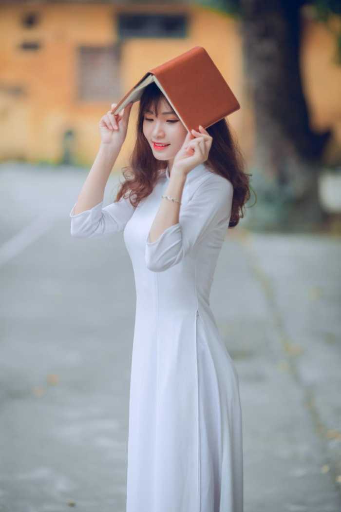 Nữ sinh tạo dáng chụp ảnh che đầu bằng quyển vở